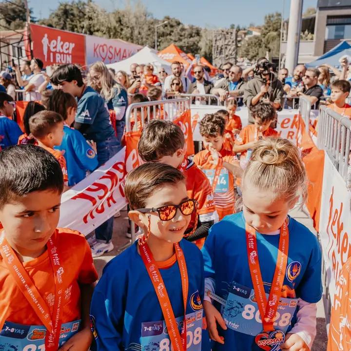 Grupa dzieci z numerami startowymi i medalami po biegu